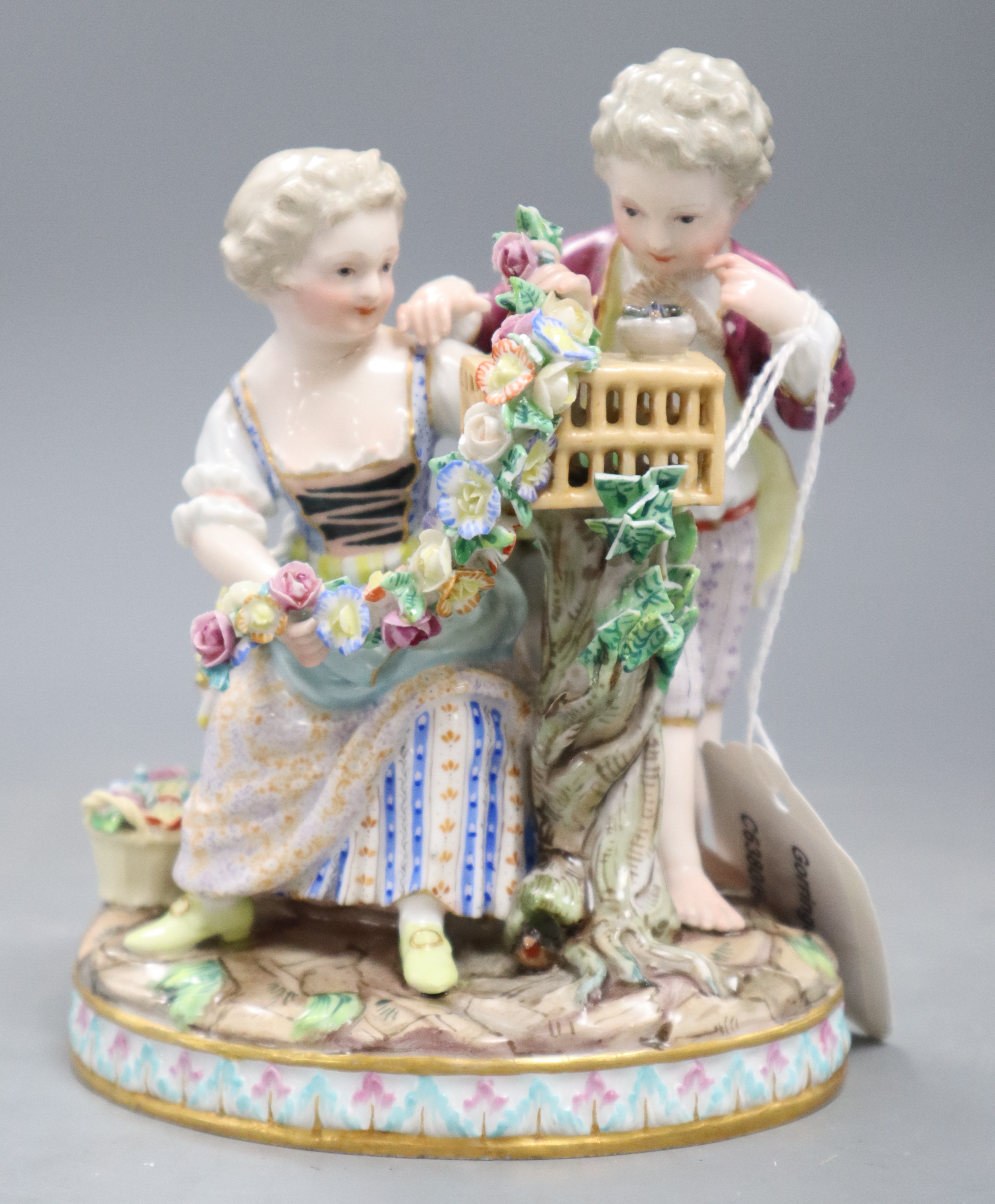 A Meissen figure group of a boy and girl with cage and garland, underglaze blue crossed sword marks, height 15cm